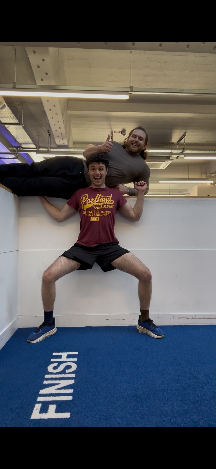 Two people sharing a playful lifting pose in the gym