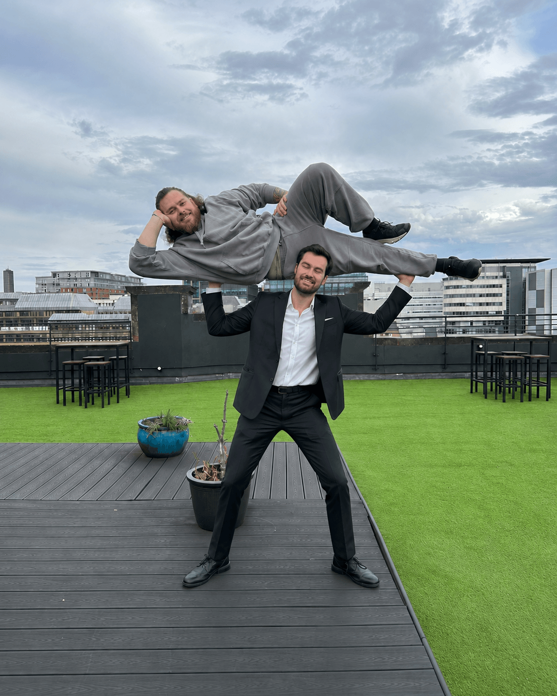 Two people striking a playful lifting pose on a rooftop terrace